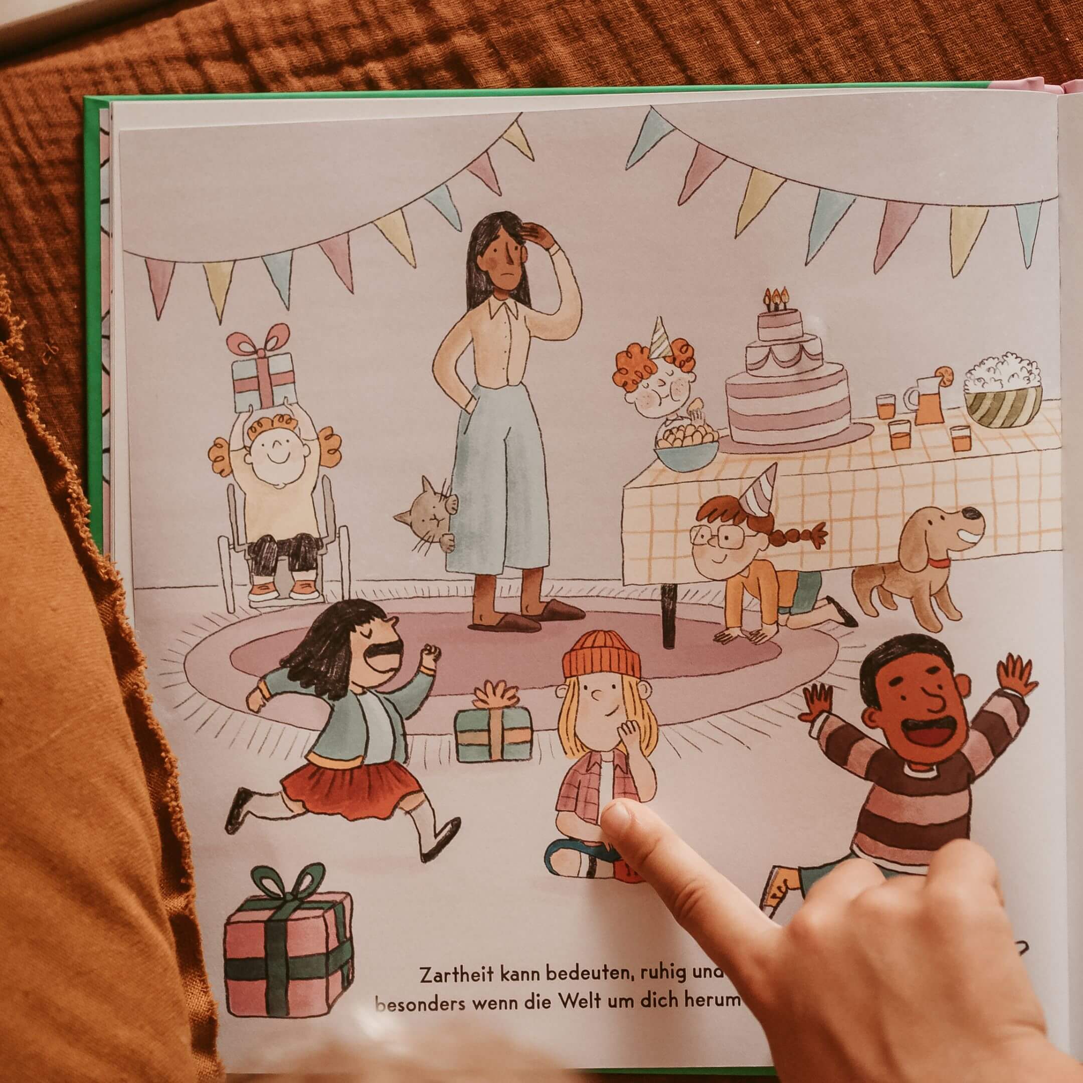 Bei einer Geburtstagsfeier spielen Kinder mit Luftballons und Kuchen, während eine lächelnde Frau zusieht. Ein Kind im Rollstuhl nimmt freudig am Spiel teil. "Ich bin zart. Ich bin stark." von Jessica Sanders feiert die Stärke und Sensibilität eines jeden Kindes.