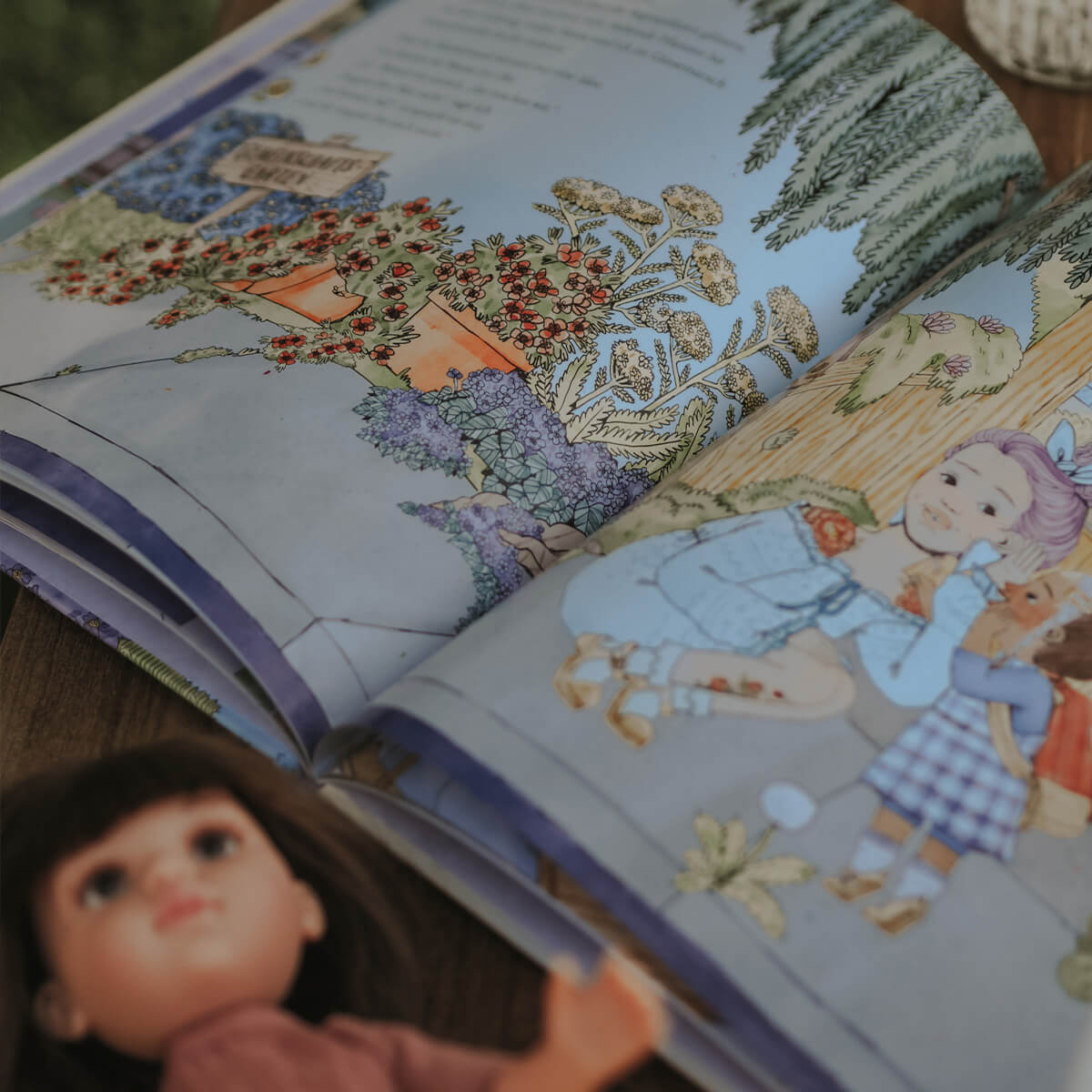 Ein aufgeschlagenes Bilderbuch zeigt eine Szene aus „Mama und Mami und ich: Die große Vermissung“ von Nina LaCour, in der zwei Kinder fröhlich inmitten blühender Pflanzen sitzen. Im Vordergrund liegt eine braunhaarige Puppe.