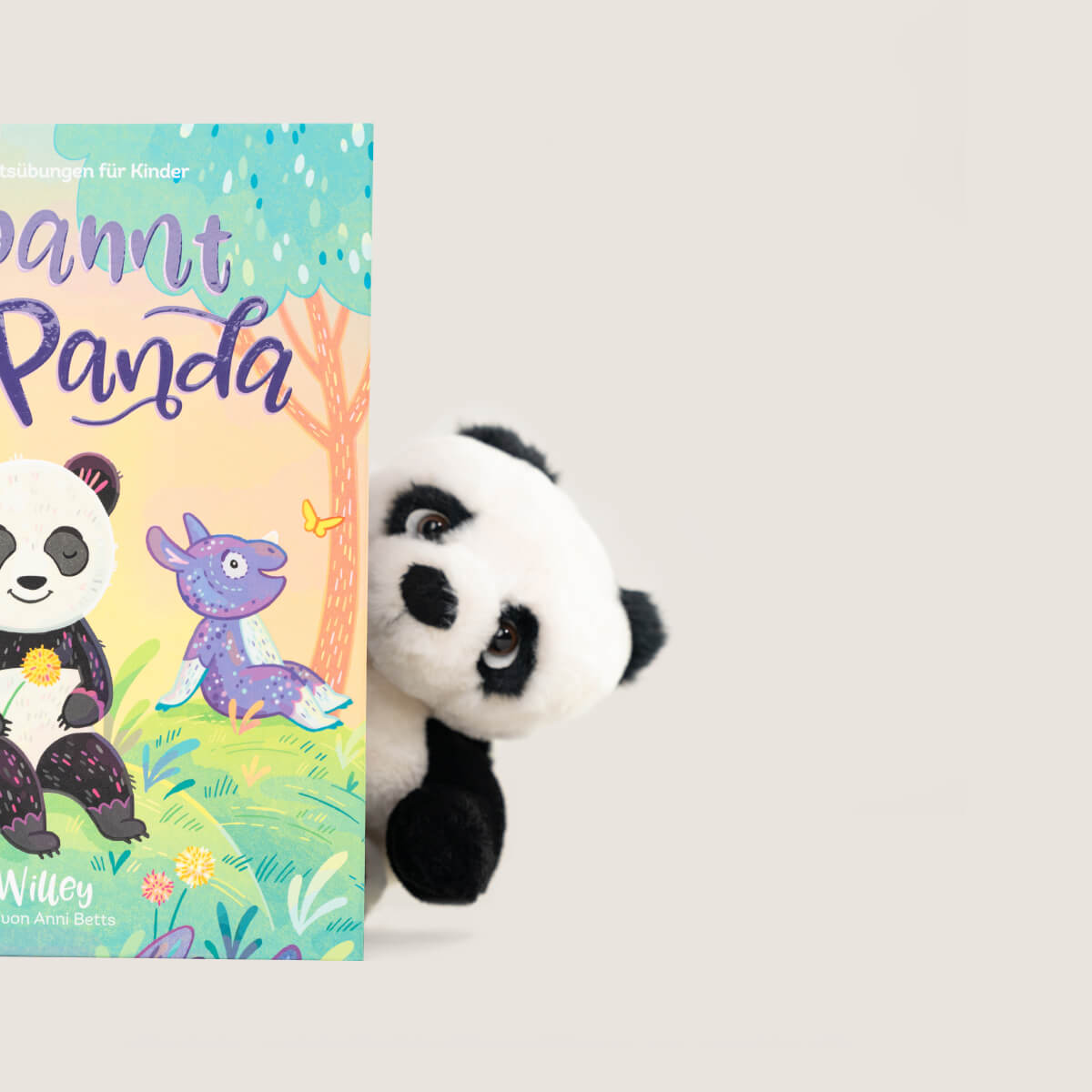 Ein Bukowski Schweden Panda-Plüschtier lugt hinter dem farbenfrohen Kinderbuch „Achtsam wie ein Panda“ von Kira Willey hervor. Auf dem Cover sind ein lächelnder Panda und ein lilafarbener Dinosaurier illustriert. Der Hintergrund ist schlicht und hell gehalten.