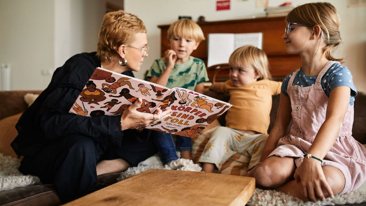 Mutter ließt drei Kindern ein Buch vor. 