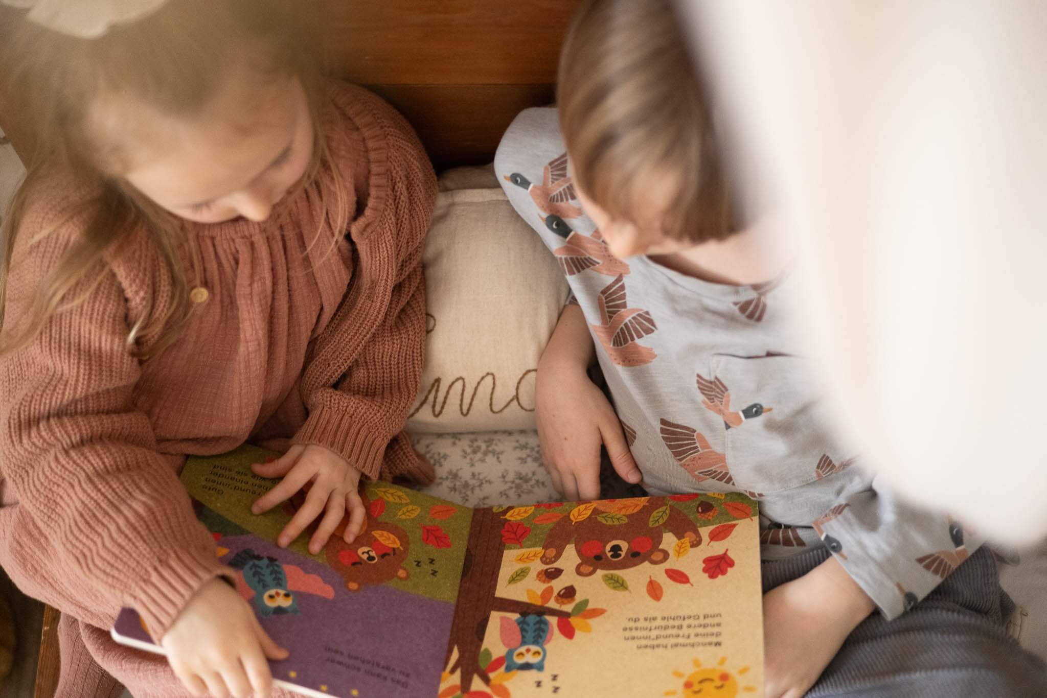Zwei Kinder blättern durch das Buch "Hilfe brauchen ist okay" von Annalies Draws
