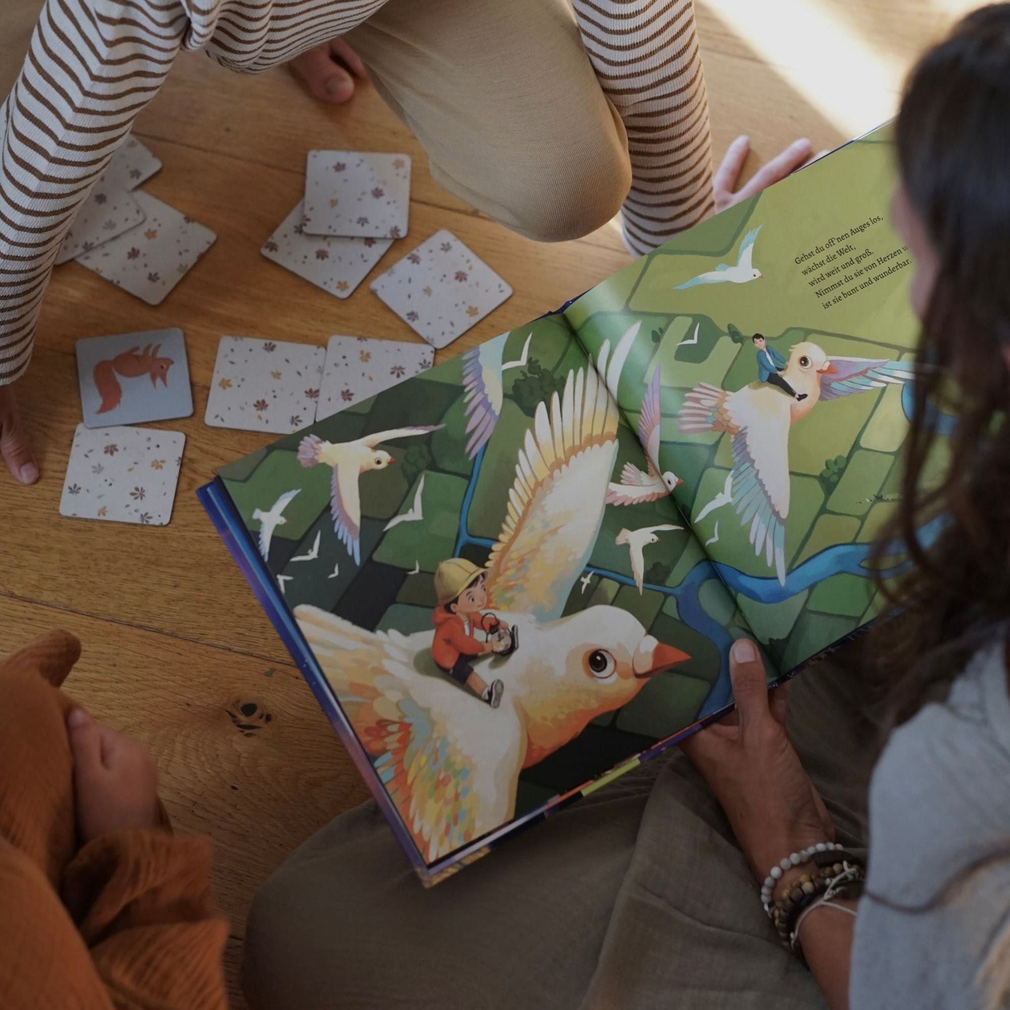 Zwei Personen sitzen auf einem Holzboden und lesen 