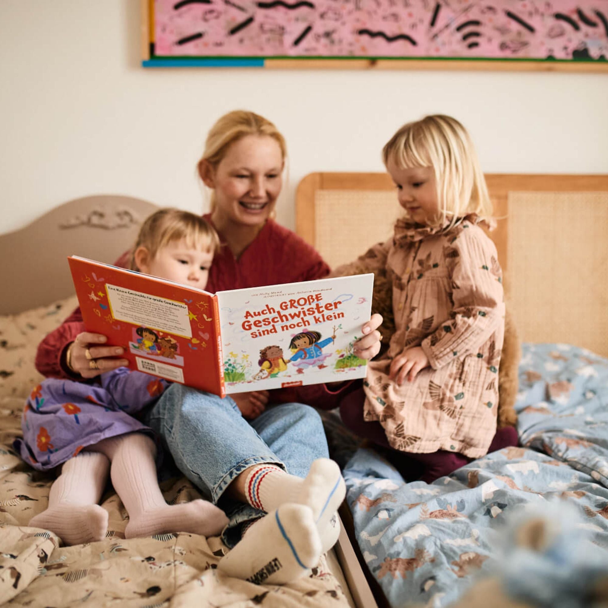 Eine Frau liest zwei Mädchen auf einem Bett 